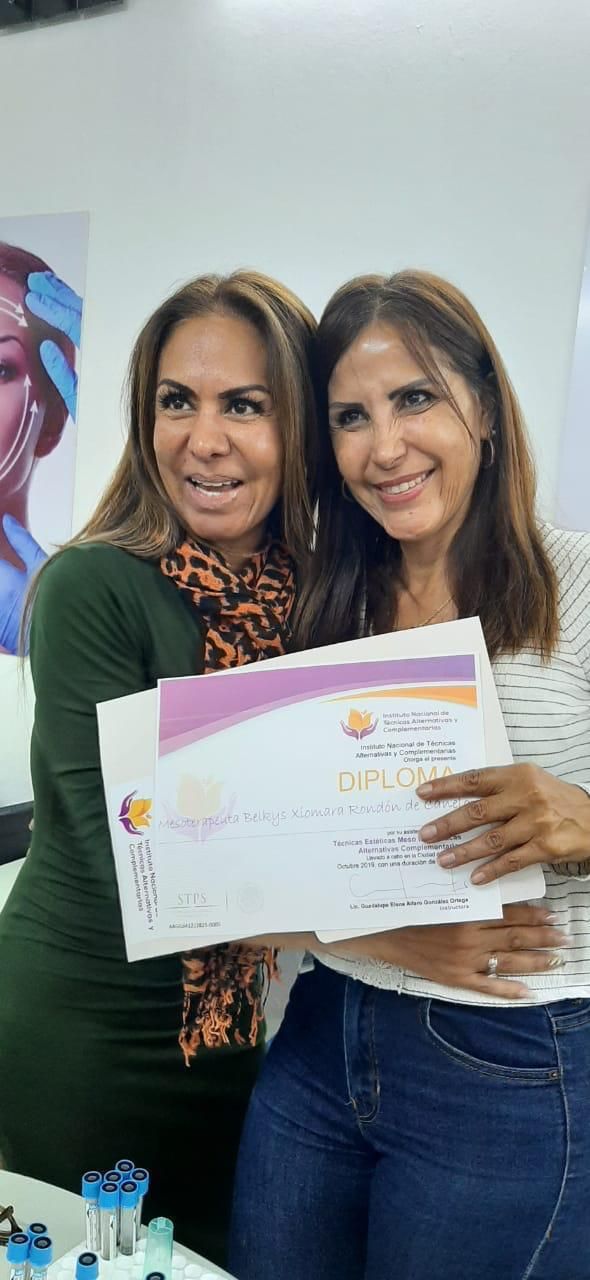 Dos mujeres sonriendo; una sostiene su diploma del instituto